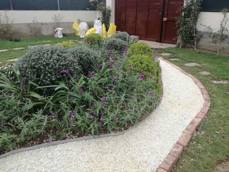 Camino de piedra entre arbustos y macizos florales